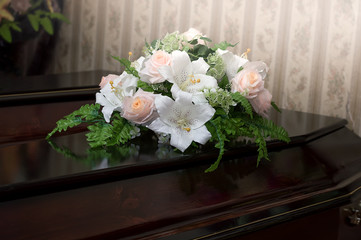 A wooden coffin of dark color is decorated with flowers. Funeral, burial. Death.