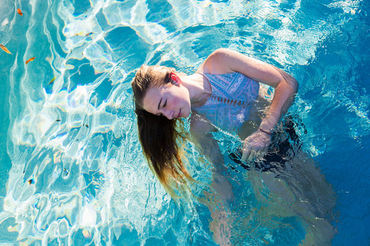 A teenage girl swimming in a pool, head back hair floating in the water. ,St Simon's Island