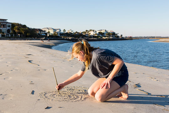 A teenage girl playing in sand dunes, at the beach,St Simon's Island