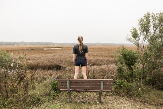 Teenage girl standing on a bench looking out over marshes, St. Simon's Island, Georgia,St Simon's Island
