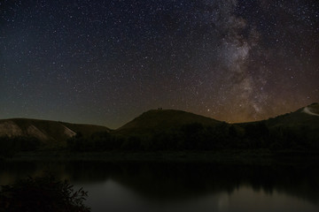 Fototapeta na wymiar Milky Way stars in the sky. Night landscape with hills by the river.
