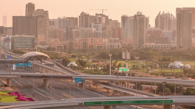 Dubai Golf Course with a cityscape of Gereens and tecom districts at the background aerial timelapse early morning during sunrise. Traffic on sheikh zayed road with junction