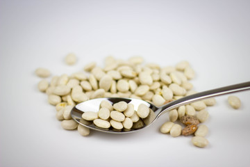 weiße Bohnen mit einem Löffel unschärfe isoliert