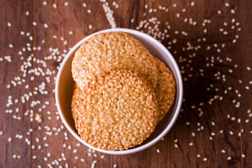 Round sesame cookies with milk and juice on the table.