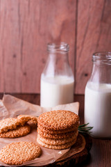 Round sesame cookies with milk and juice on the table.