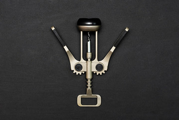 Metal corkscrew for bottles on a black background. Flat lay, copy space.