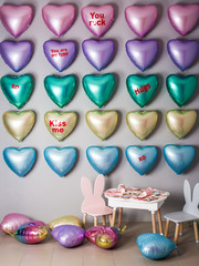 A wall of balloons in the form of hearts of different colors.