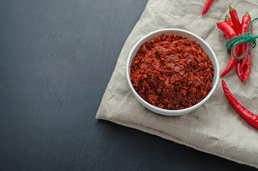 Traditional adjika hot chili pepper sauce paste harissa. Tunisia, georgian and arabic cuisine. Horizontal orientation. Copy space