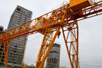 A large modern construction site in the construction of buildings and houses with appliances and many large high tower and stationary industrial powerful cranes and building materials
