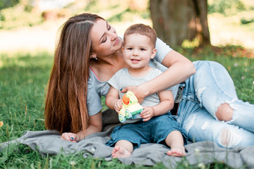 Mother with little son spend time together in green park.