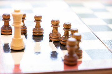 Chess pieces on a chessboard. The king is surrounded by pawns.