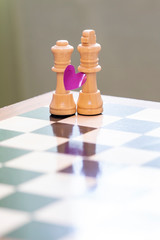 Love and marriage. Chess pieces on a chessboard with a heart symbol.