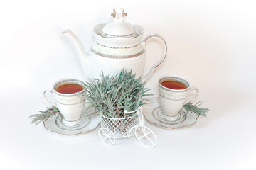 Miniature white Bicycle decorated with green lavender branches. Two porcelain tea cups and a teapot on a white background