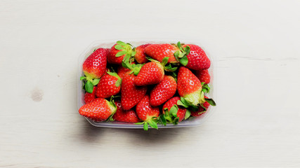 Fresas en bandeja transparente, sobre la mesa