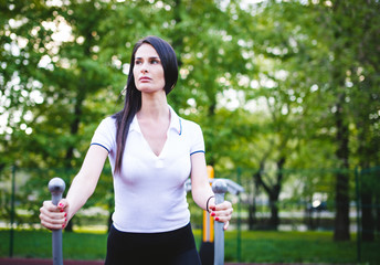 athletic and flexible girl engaged in athletics on the background of the city, she trains in the morning on the street, a woman does stretching and gymnastic tricks