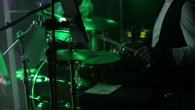 Young man playing drums on stage. Concert. Neon light. Live music background. Drum kit on stage lights performance. Festival and show background