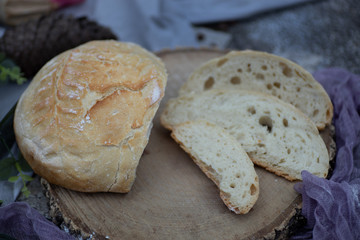 Artisan bread bun sliced on tablecloth in garden