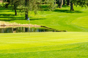 Obraz premium Golf course with gorgeous green and pond.