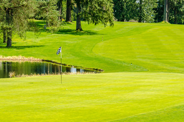 Obraz premium Golf course with gorgeous green and pond.
