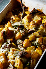 Girl picks up a spoonful of baked potatoes with mushrooms and cheese