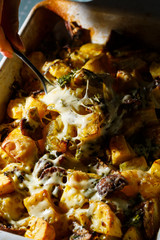 Girl picks up a spoonful of baked potatoes with mushrooms and cheese