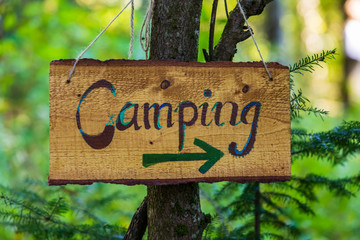 Une vue rapprochée floue d& 39 un panneau de camping directionnel en bois fabriqué à la main, camping forestier pendant le festival multiculturel célébrant la terre et la nature