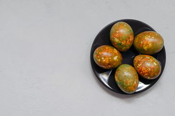 modern trendy marble Easter eggs of original coloring on a dark plate on a light background closeup with a copy space