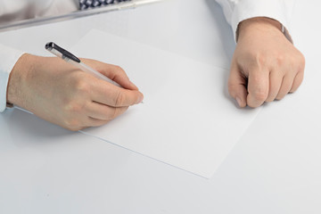 businessman writes on a sheet of white paper. Dressed in a shirt and tie. Close-up