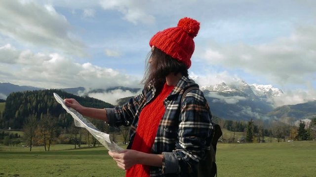 Young lady traveler with a backpack and a map on the background of the Alps. Active leisure, lifestyle sports, hiking in the mountains. Travelling in Europe.