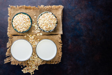 Oat milk. Organic oat milk on a dark background. Vegan non dairy alternative milk. Healthy vegan milk on sackcloth. Top view. Flat lay
