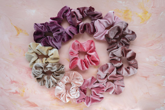 Collection of trendy velvet scrunchies on pink background. Diy accessories and hairstyles concept.