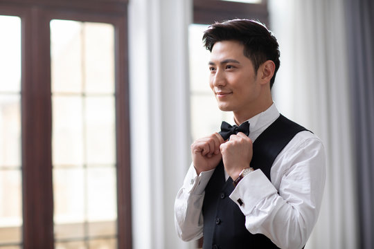 Happy young Chinese man getting dressed at home
