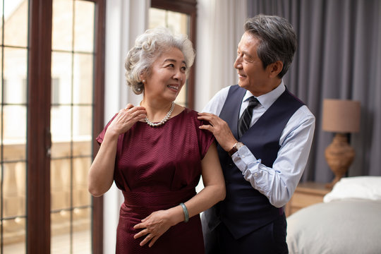 Happy senior Chinese couple getting dressed at home