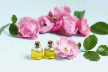 Fototapeta na wymiar Rosehip cosmetic oil in mini bottles and pink rosehip flowers. Spa treatments for relaxation.