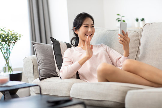 Happy young Chinese woman on video call on sofa