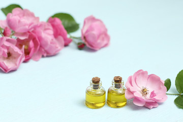 Obraz na płótnie Canvas Rosehip cosmetic oil in mini bottles and pink rosehip flowers. Spa treatments for relaxation.