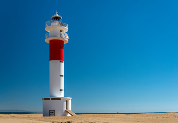 View of the El Fangar lighthouse, at the mouth or delta of the Ebro river, in Tarragona (Spain), during a sunny summer day.