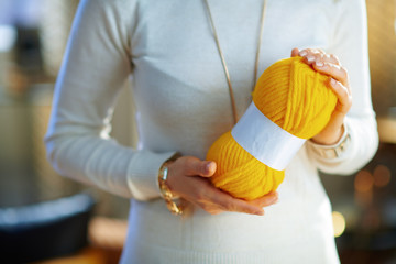 Closeup on young woman holding yellow knitting yarn hunk