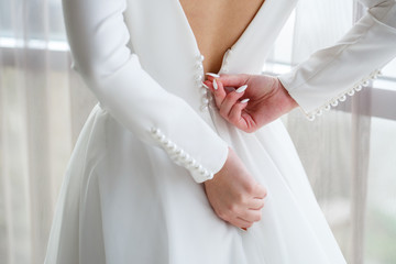 Fototapeta na wymiar Bride zips zipper on her wedding white dress