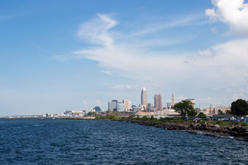 Beautiful summer landscape, which depicts the rocky shore of the lake, waves on the water and in the distance are the pain of skyscrapers. View of city of Cleveland,Ohio,USA from the lake Erie