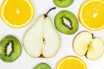 close up sliced fresh colorful fruits pear kiwi orange apple on a white background