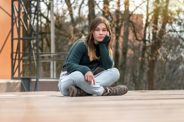 Portrait of a lonely sitting beautiful young teenage girl