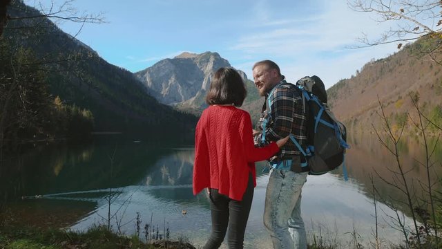 Couple Looking out over an Austrian lake and Alps with map in hands. Love, travel, lifestyle concept.