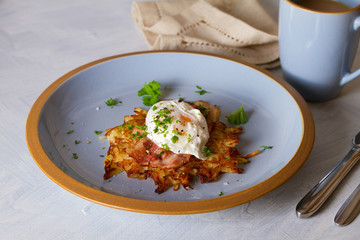 Potato cake with  bacon and poached egg, garnished with spring onion and parsley. Vegetable fritters, pancakes