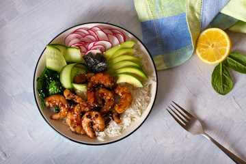 Honey soy shrimp rice bowl with spinach, radish cucumber, seaweed and avocado. View from above, top view