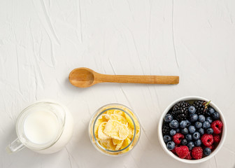 Ingredients for a healthy breakfast - cornflakes, berries, milk on a white background