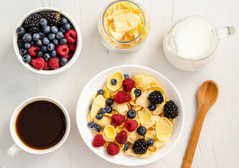 Ingredients for a healthy breakfast - cornflakes, berries, milk and coffee on a white background