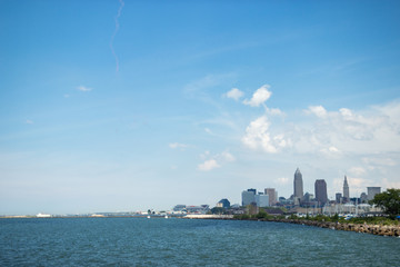 Obraz premium Beautiful summer landscape, which depicts the rocky shore of the lake, waves on the water and in the distance are the pain of skyscrapers. View of city of Cleveland,Ohio,USA from the lake Erie