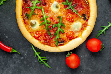 tasty Italian pizza with tomato, cheese, quail eggs sausage  on a stone background
