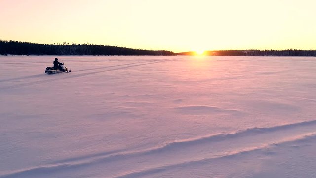 A man is on a snowmobile on a large frozen lake. Filmed in northern Quebec (Canada).